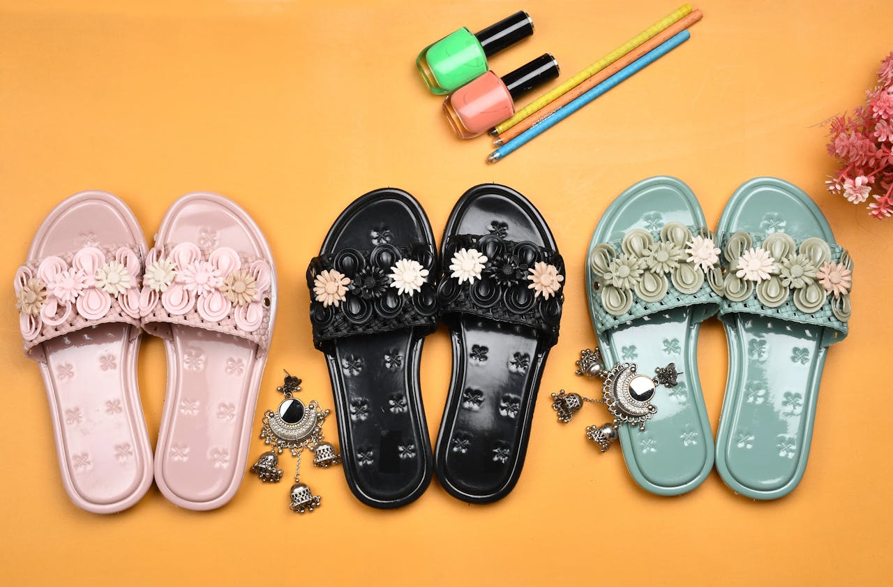 services-04 Vibrant floral slippers with nail polish and earrings on a yellow background. Perfect studio shoot for lifestyle products.